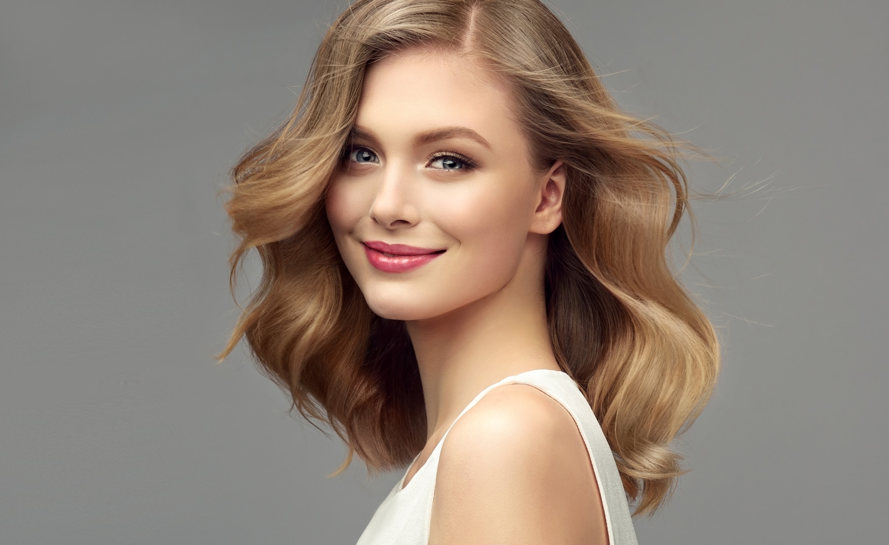 A woman with full, curly hair from PRP hair restoration treatment smiling at the camera. A woman with full, curly hair from PRP hair restoration treatment smiling at the camera.